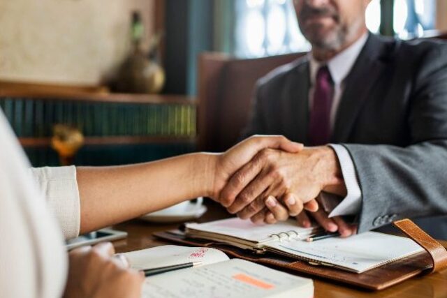 a lawyer and his client shake hands after meeting about their medical malpractice case.