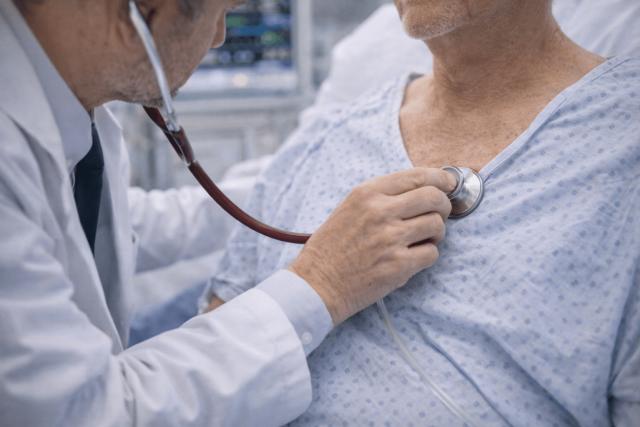 Doctor listens to a patient’s heart with a stethoscope, checking for murmurs or signs of infection