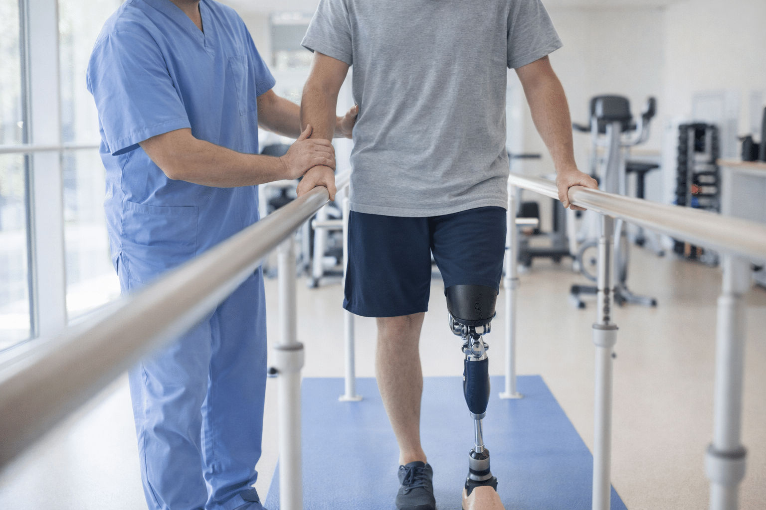Physical therapist helping an amputee patient walk with a new prosthetic leg in a rehab center